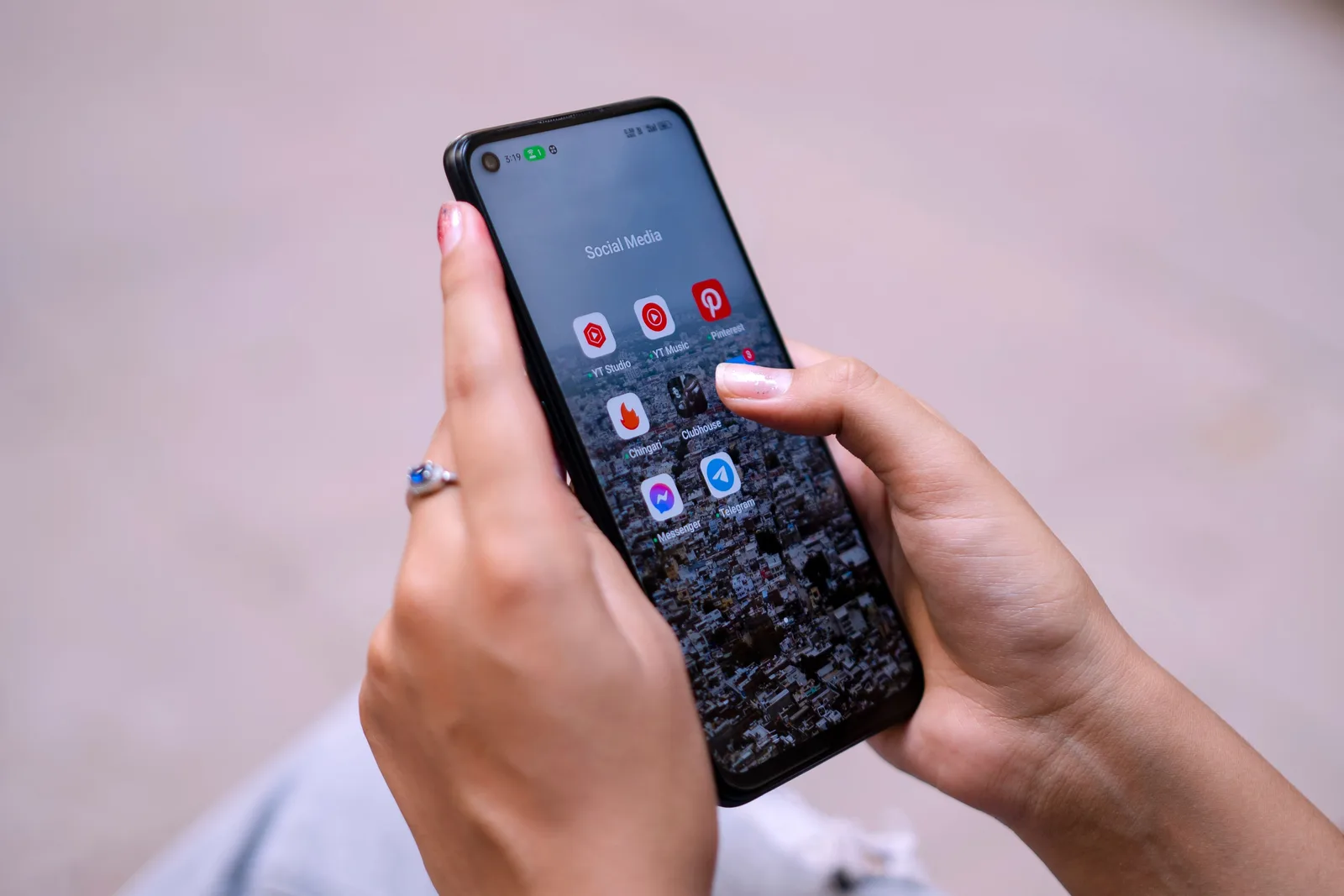 Close-up of hands holding a smartphone displaying social media apps, emphasizing digital connectivity. Five critiques of social media, weighed