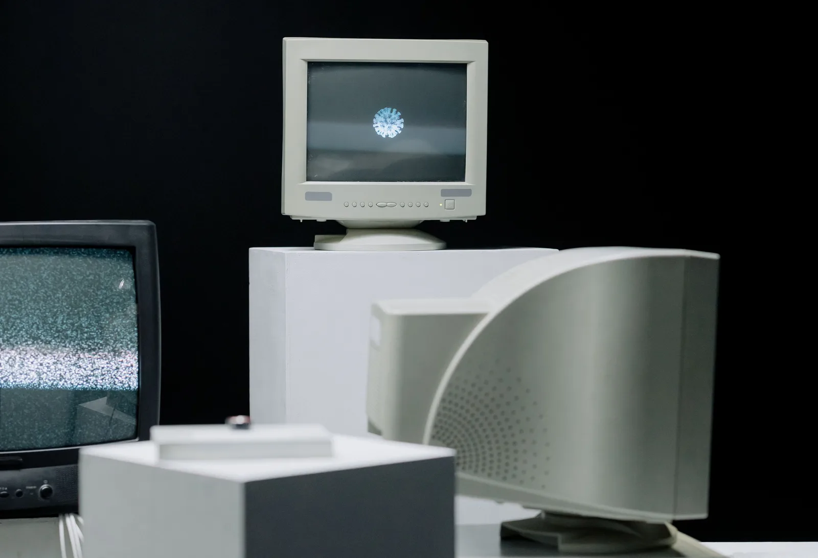 Vintage monitors displayed with static screens in a dark studio setting. Which early social network truly came first, and why does no one agree